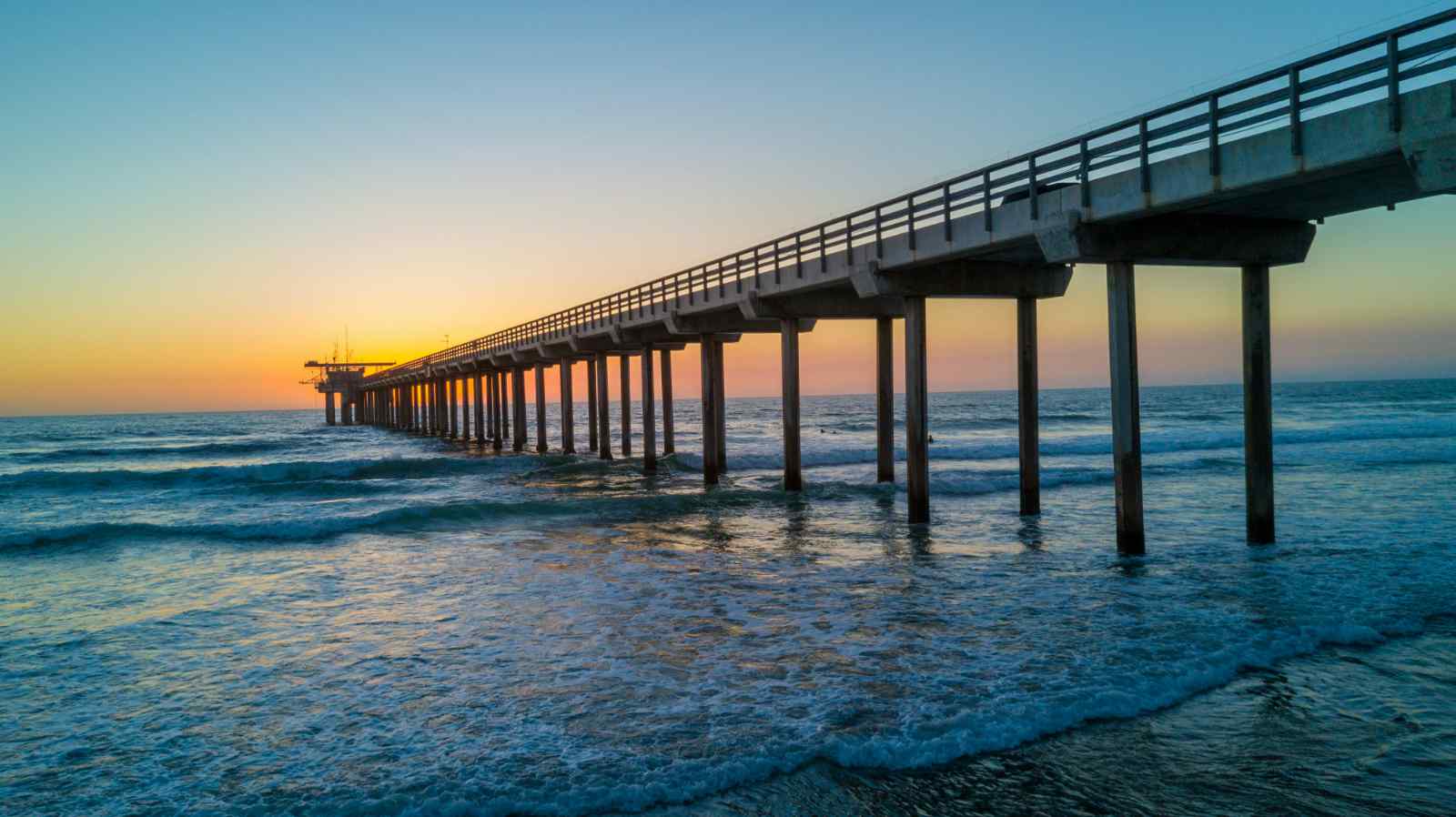 Pier on a beach at sunset.